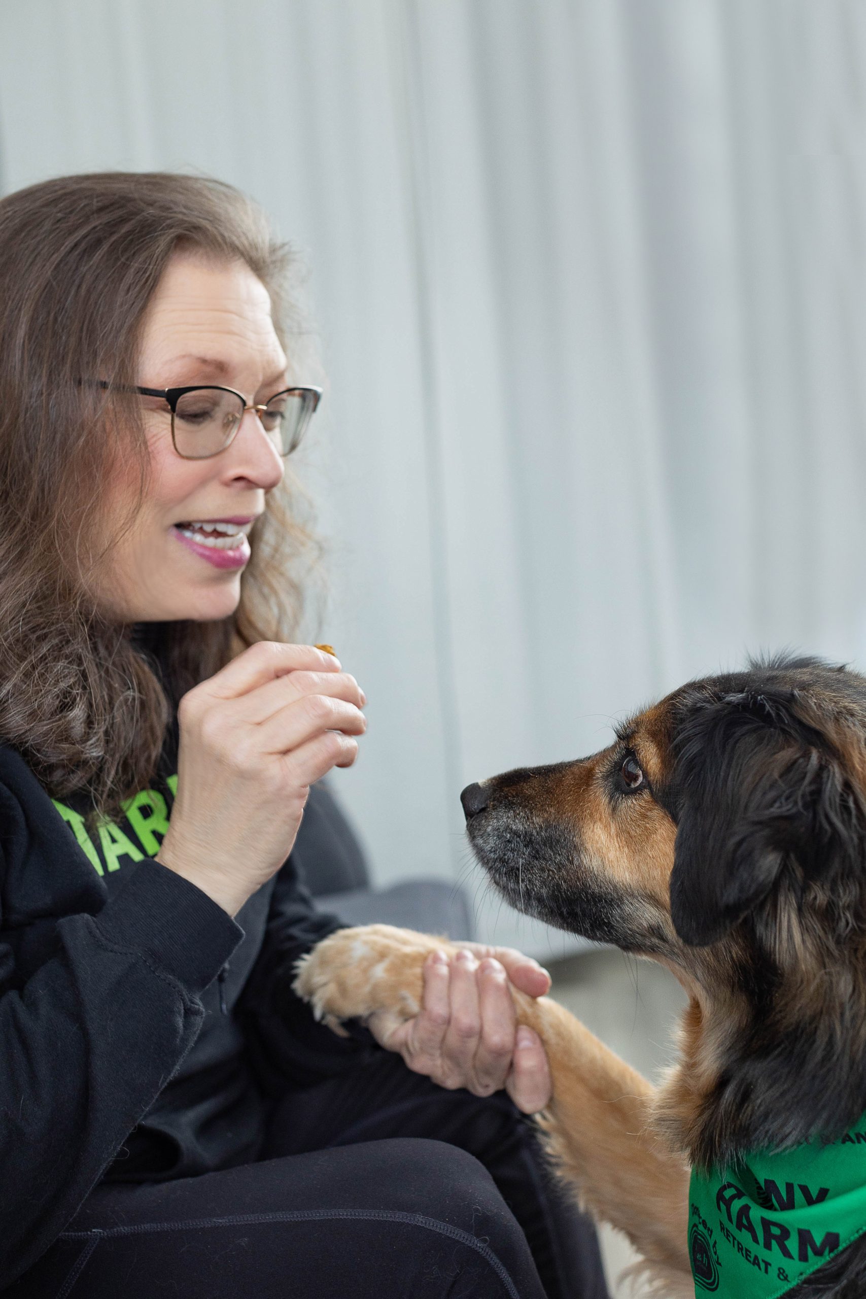 A volunteer shares a quiet moment with a rescue dog wearing a Harmony bandana